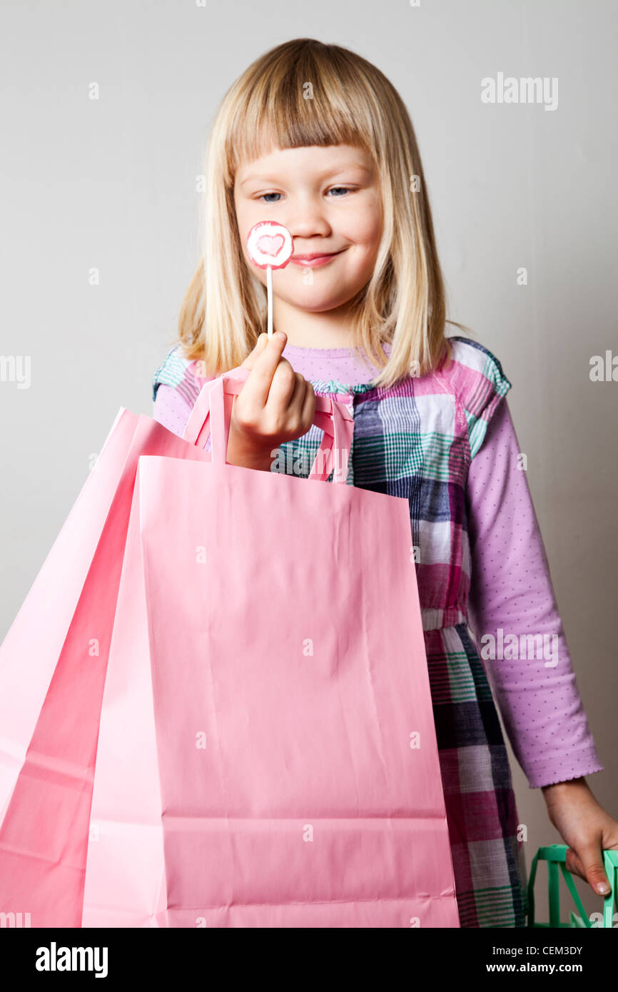 Cute little Girl with shopping bags and a heart lollipop Banque D'Images