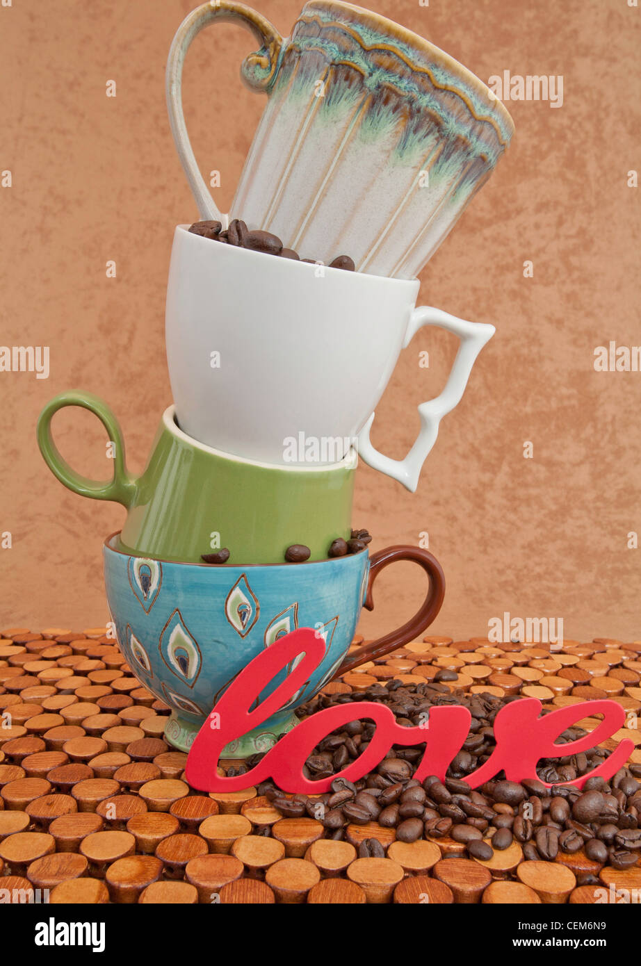 Quatre tasses de café pile sur le dessus de l'autre avec des grains de café et le mot amour sur le comptoir en bois et stuc brown background Banque D'Images