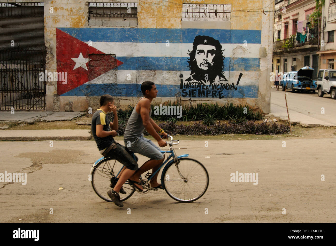 Gars marcher avec location en face d'un drapeau cubain et emblématiques du Che Guevara peinture à La Havane, Cuba ville Banque D'Images