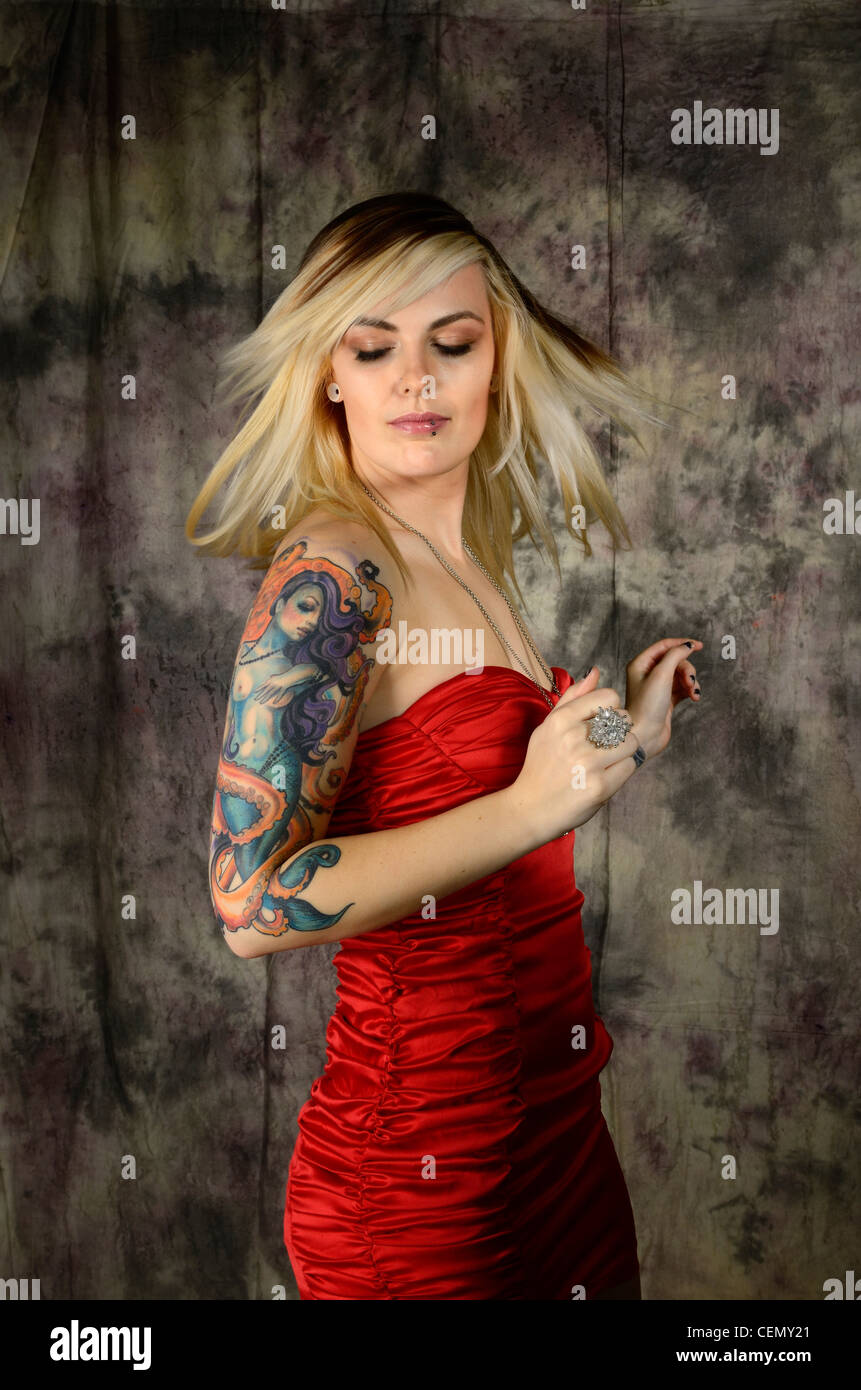 Femme de tourner sa tête en robe rouge scrunch avec tatouage et piercing lèvre bras Banque D'Images