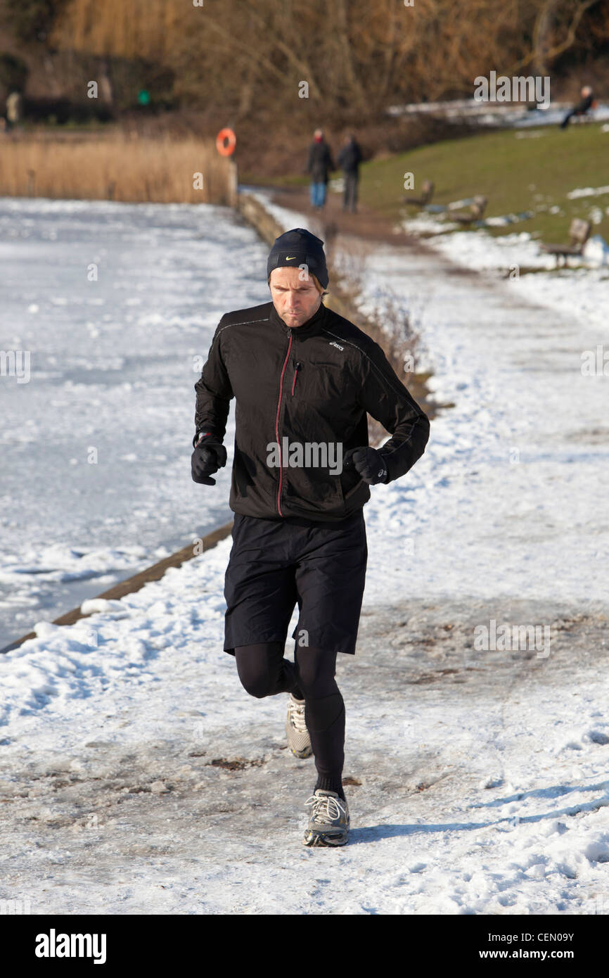 Homme du jogging le long chemin gelé, Hampstead Heath, London, England, UK Banque D'Images