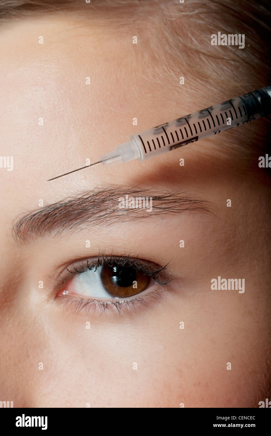 Étape par étape de Femme avec cheveux brune, tenant une seringue sur son front, looking at camera Banque D'Images