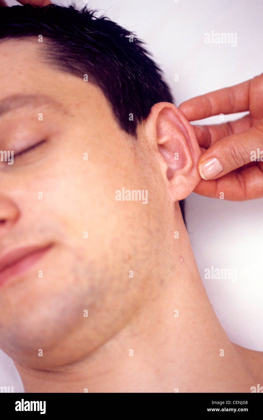 Massage complet du corps : Close up portrait of male avec les cheveux foncés tête tourna légèrement massée de l'oreille, les yeux fermés Banque D'Images