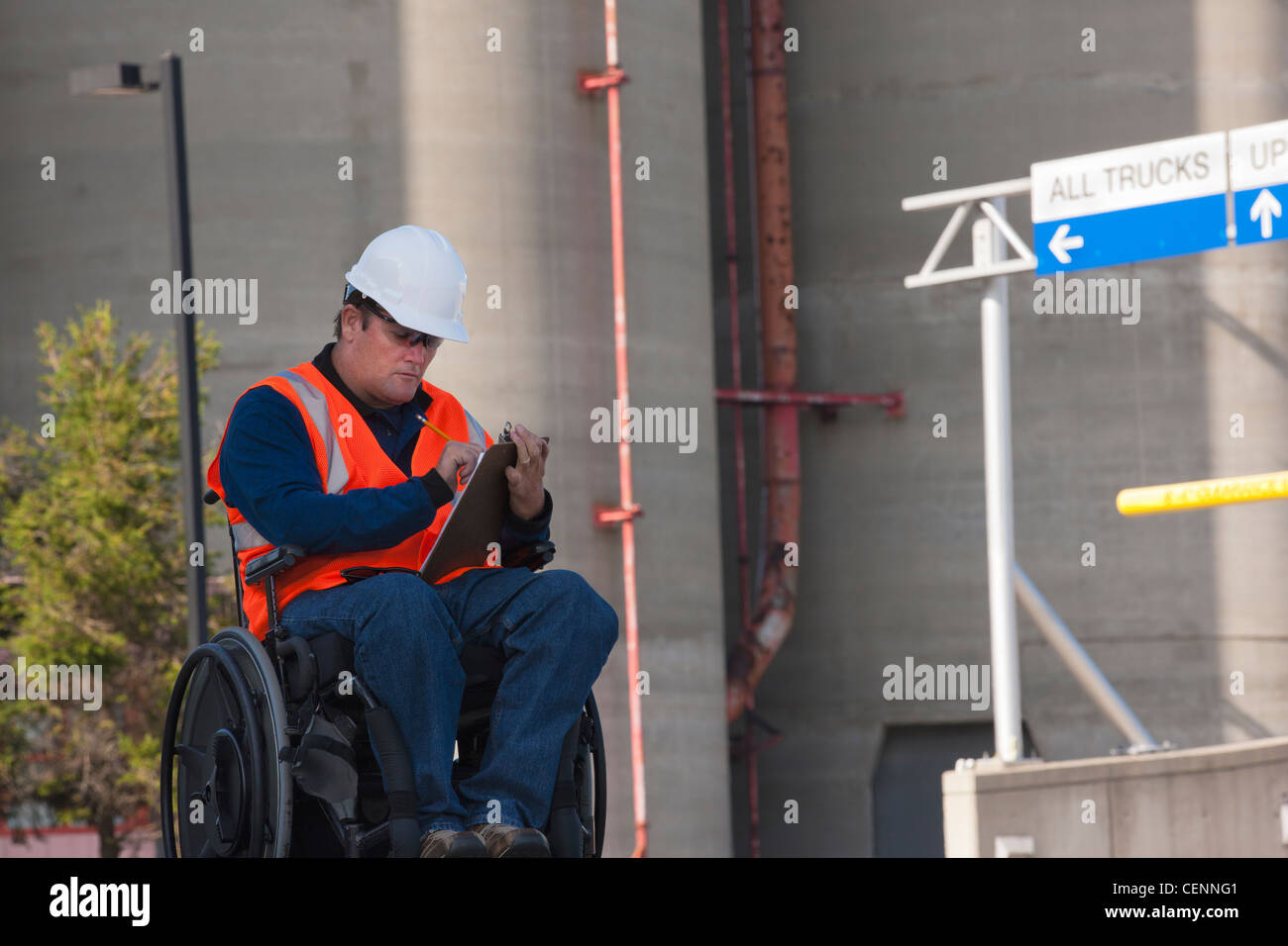 Ingénieur des installations dans un fauteuil roulant à l'extérieur de l'inspection des réservoirs de stockage en vrac et de l'enregistrement des données Banque D'Images