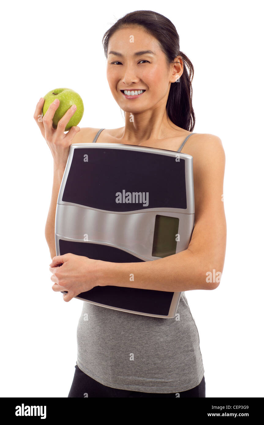 Jeune femme en bonne santé holding apple et une balance numérique isolated over white background Banque D'Images
