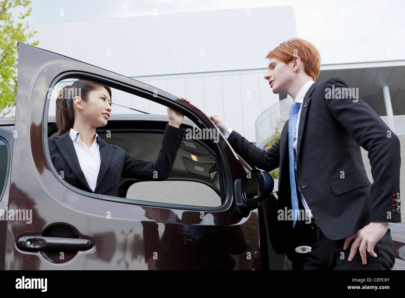 Businessman and businesswoman standing by a car Banque D'Images