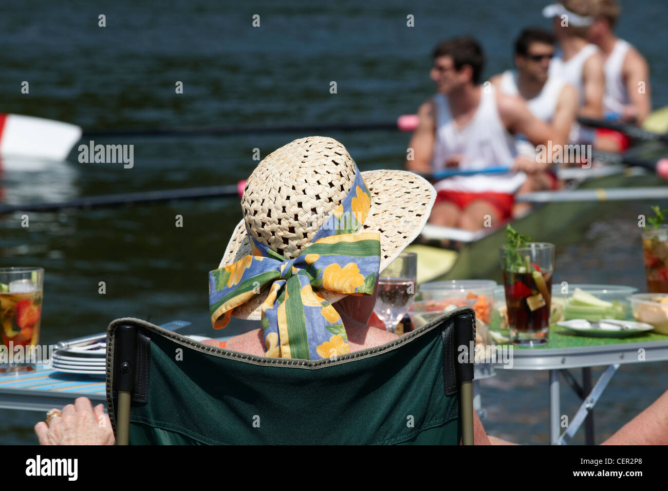 Une femme détente sur la rive du fleuve avec un verre de regarder un Pimms race à l'assemblée annuelle Henley Royal Regatta. Banque D'Images