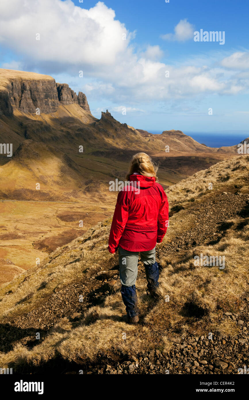 Une femme portant un imperméable rouge Walker à la recherche sur le paysage magnifique de la péninsule de Trotternish Quiraing la. Banque D'Images