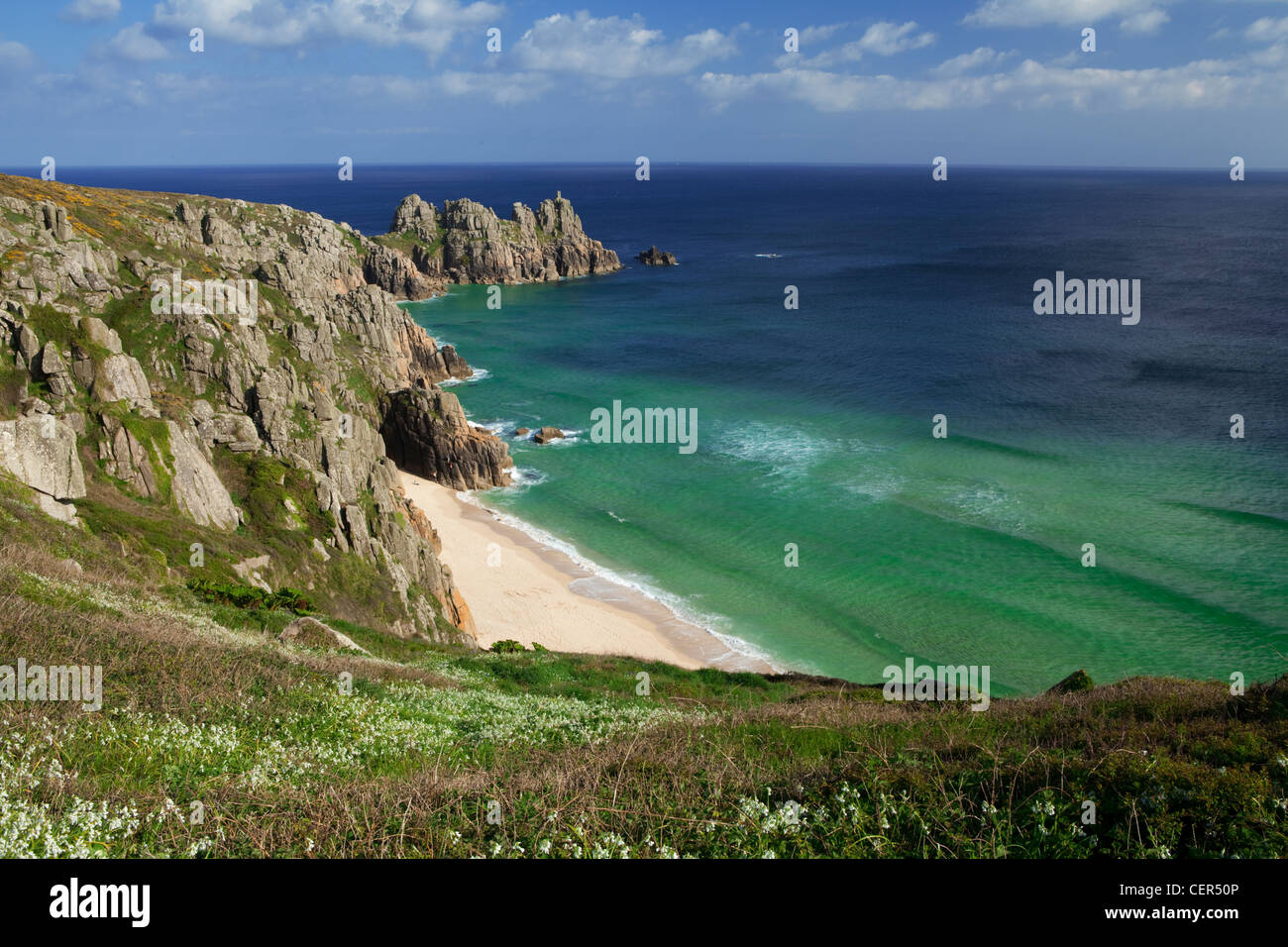 Vue le long du promontoire rocheux vers Logan Rock de Treen falaises. La baie et la plage de Porthcurno entourés par le headla rock Logan Banque D'Images