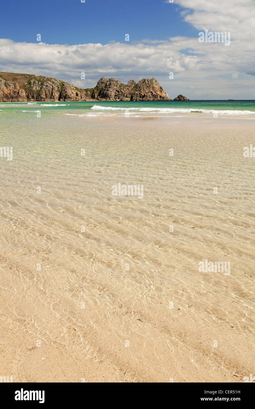 Marée basse sur la plage de sable de Porthcurno avec Logan rock dans la distance. Banque D'Images
