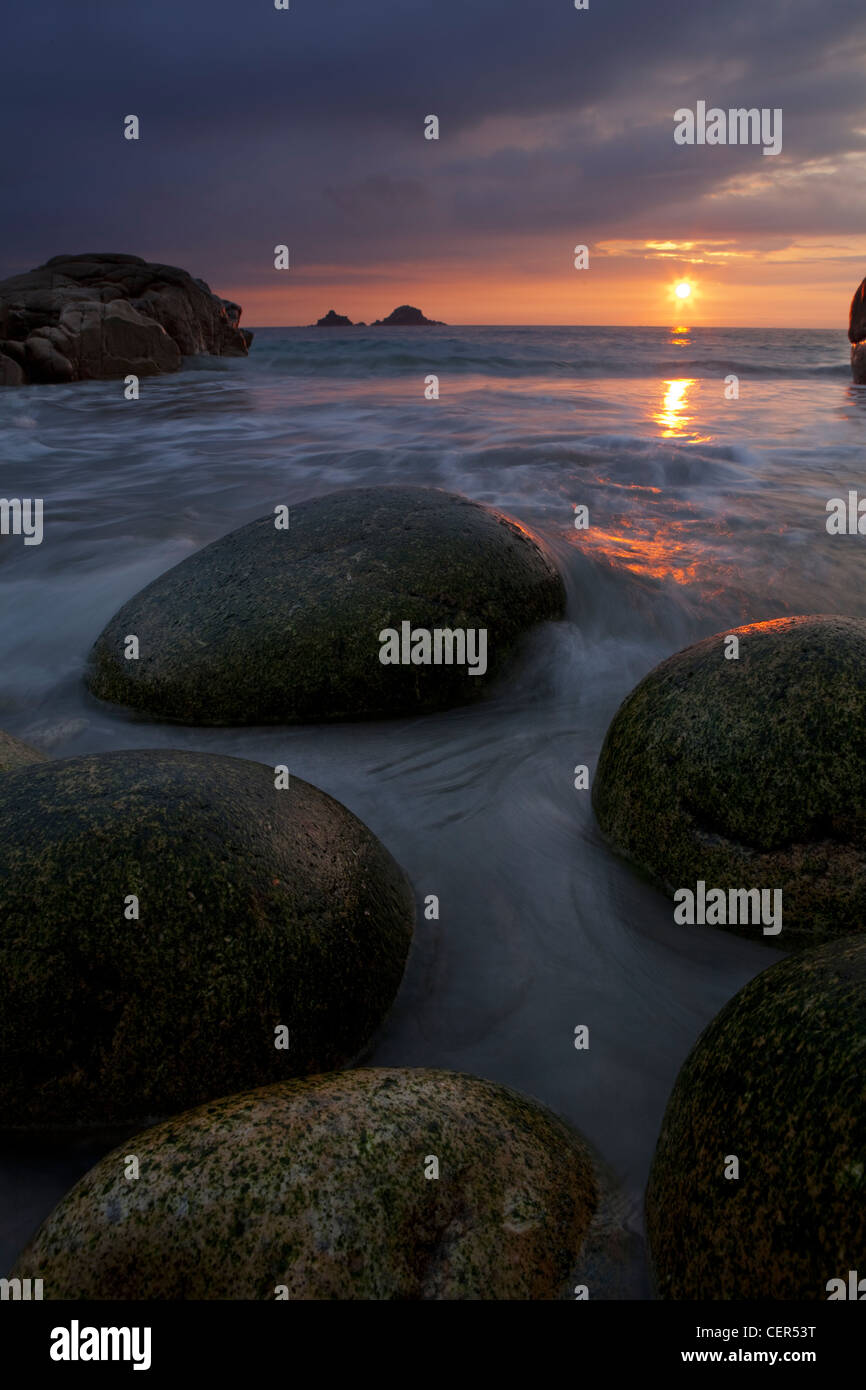 De grands rochers ovoïdes sur la plage de Porth Nanven au coucher du soleil. Banque D'Images