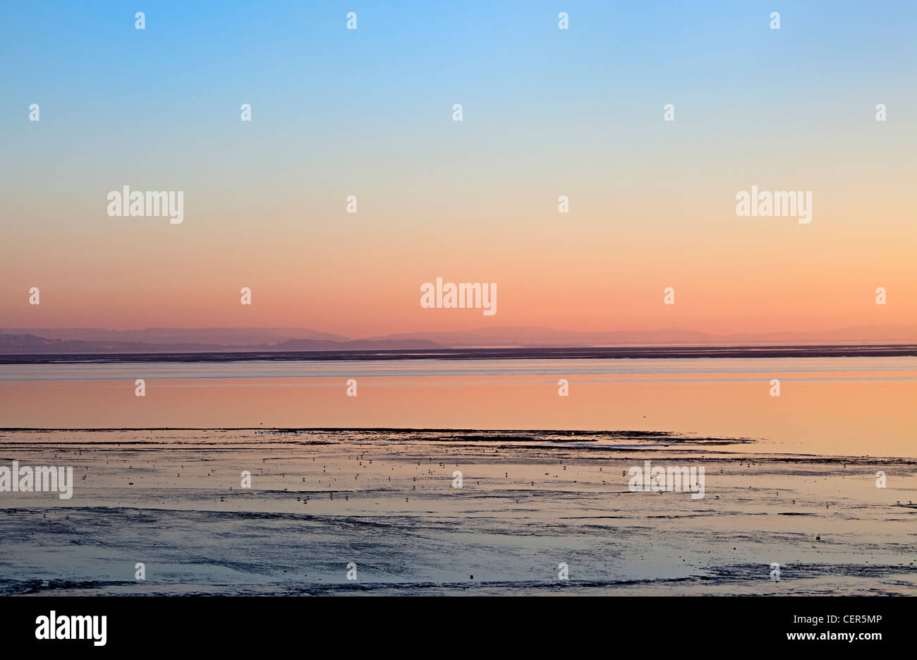 Coucher de soleil sur la plage et d'alimentation des vasières à Goldcliff près de Newport sur l'estuaire de la Severn, Gwent, au Pays de Galles, Royaume-Uni Banque D'Images