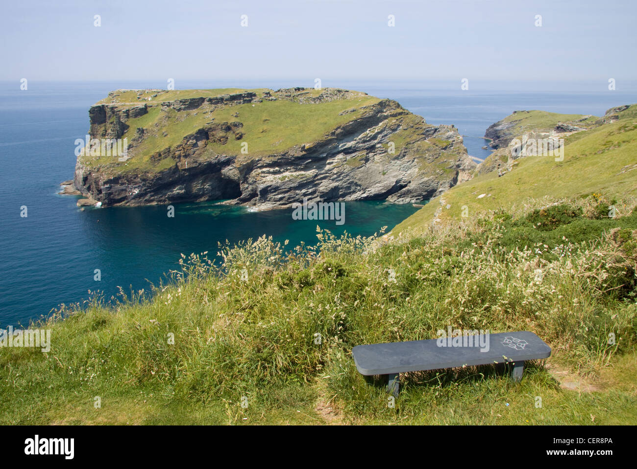 Un banc en pierre donnant sur la tête de Tintagel, le site des vestiges d'un monastère et le château. Château de Tintagel est associé à t Banque D'Images