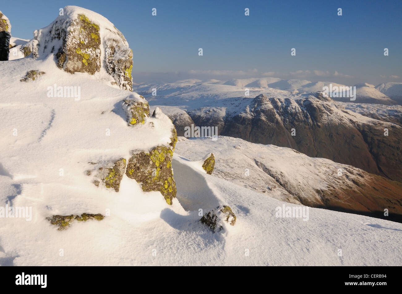 Des roches couvertes de neige sur Crinkle Crags avec les Langdale Pikes dans l'arrière-plan sur la montagne d'hiver dans le Lake District Banque D'Images