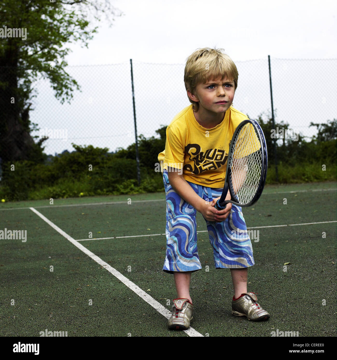 Enfant mâle portant des shorts bleu, jaune T shirt et des formateurs sur la  tenue de tennis raquette de tennis Photo Stock - Alamy