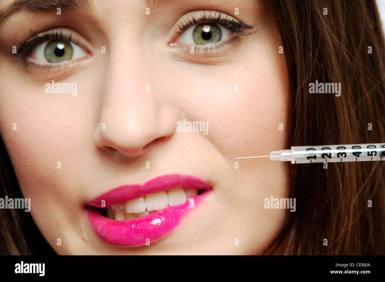 Close up de femmes avec des cheveux brune avec aiguille pointée sur la lèvre supérieure à la caméra directement à lèvre piqueurs Banque D'Images