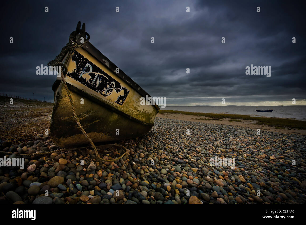 Une vieille barque jaune sur une plage de galets à Fleetwood. Banque D'Images
