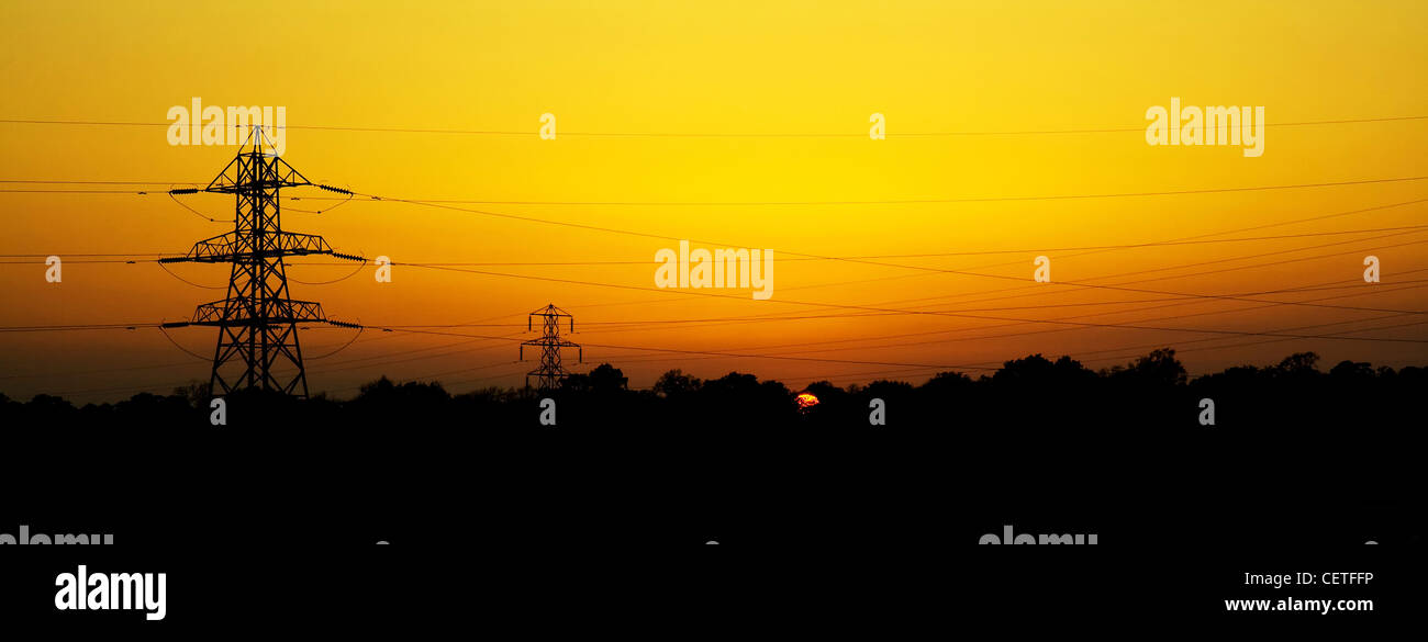 Les pylônes et les câbles électriques des silhouettes s'étendant à travers Sheffields au coucher du soleil. Banque D'Images
