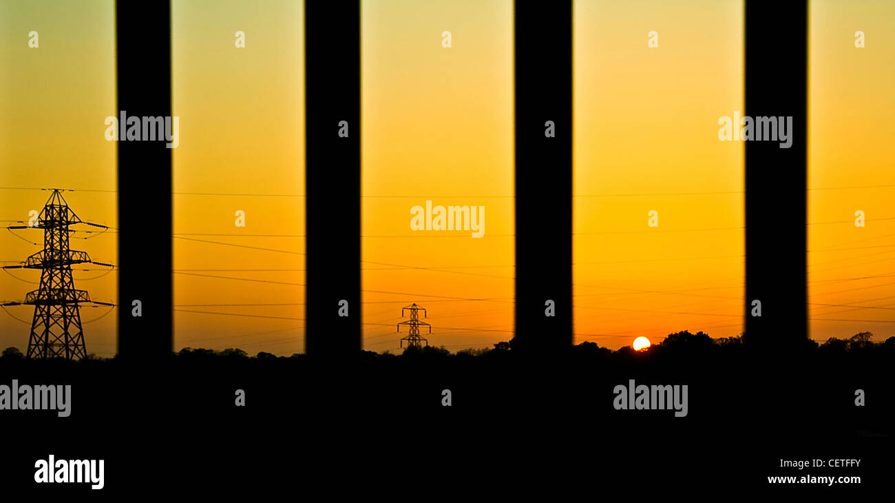 Les pylônes et les câbles électriques des silhouettes s'étendant à travers Sheffields au coucher du soleil. Banque D'Images