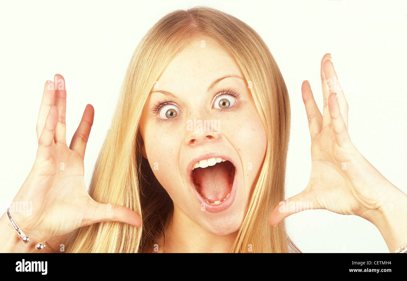 Femme avec de longs cheveux blonds yeux tout droit et d'ouvrir grand la bouche de surprise et d'autre de mains ouvertes face Banque D'Images