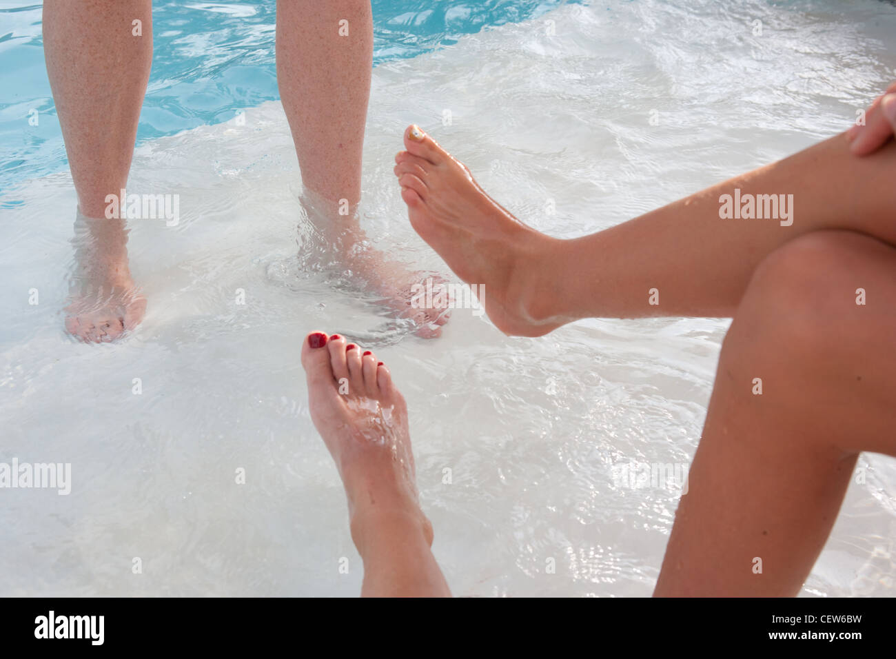 Les jambes et les pieds et près de l'eau des piscines. Trois personnes profitant de la piscine. Banque D'Images