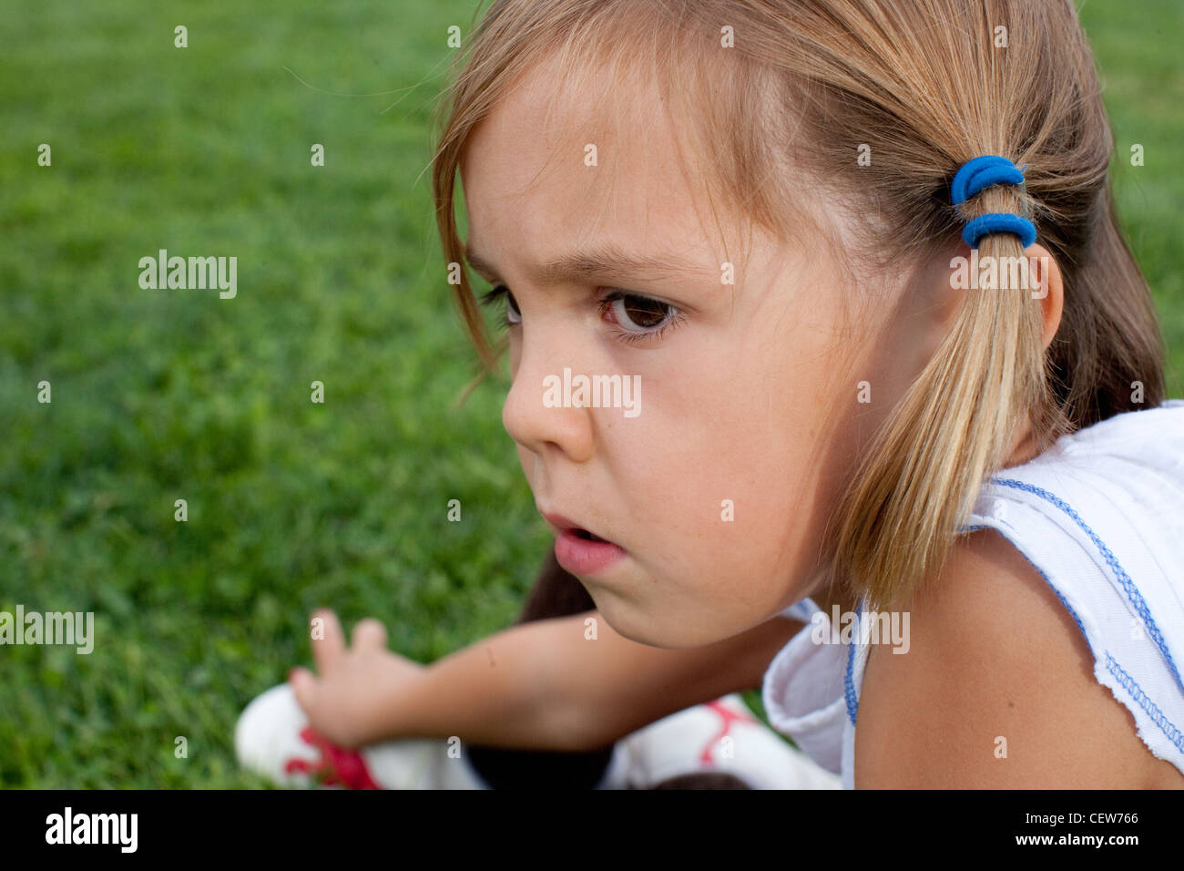 Fillette de six ans assis dans l'herbe à la grave Banque D'Images