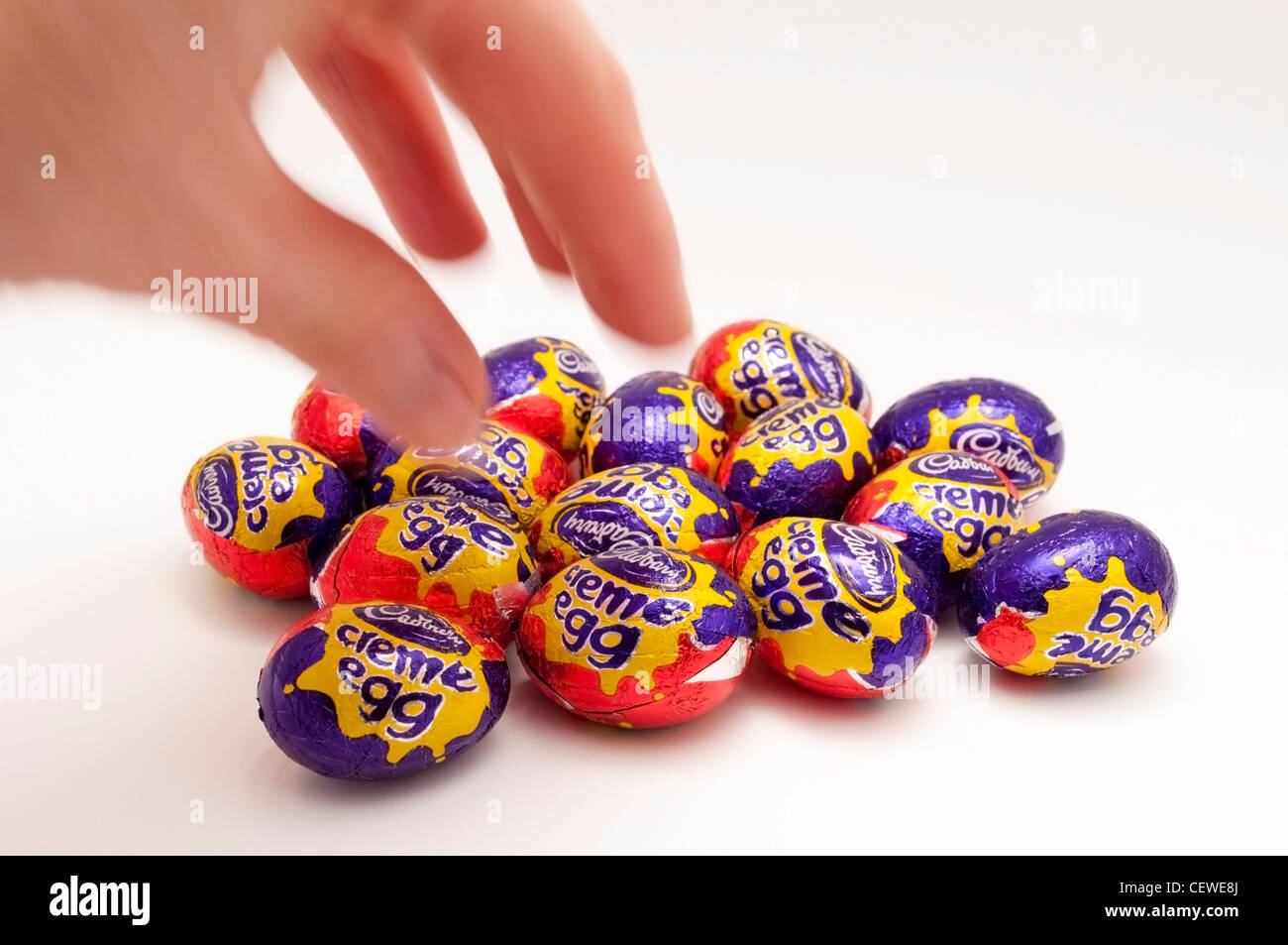 Une main se déplaçant dans de choisir un mini-Cadbury creme egg Banque D'Images