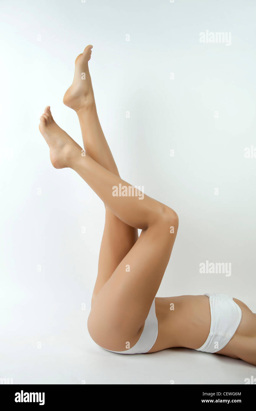 Femme allongé sur le dos en sous-vêtements avec les jambes en l'air, cropped Banque D'Images
