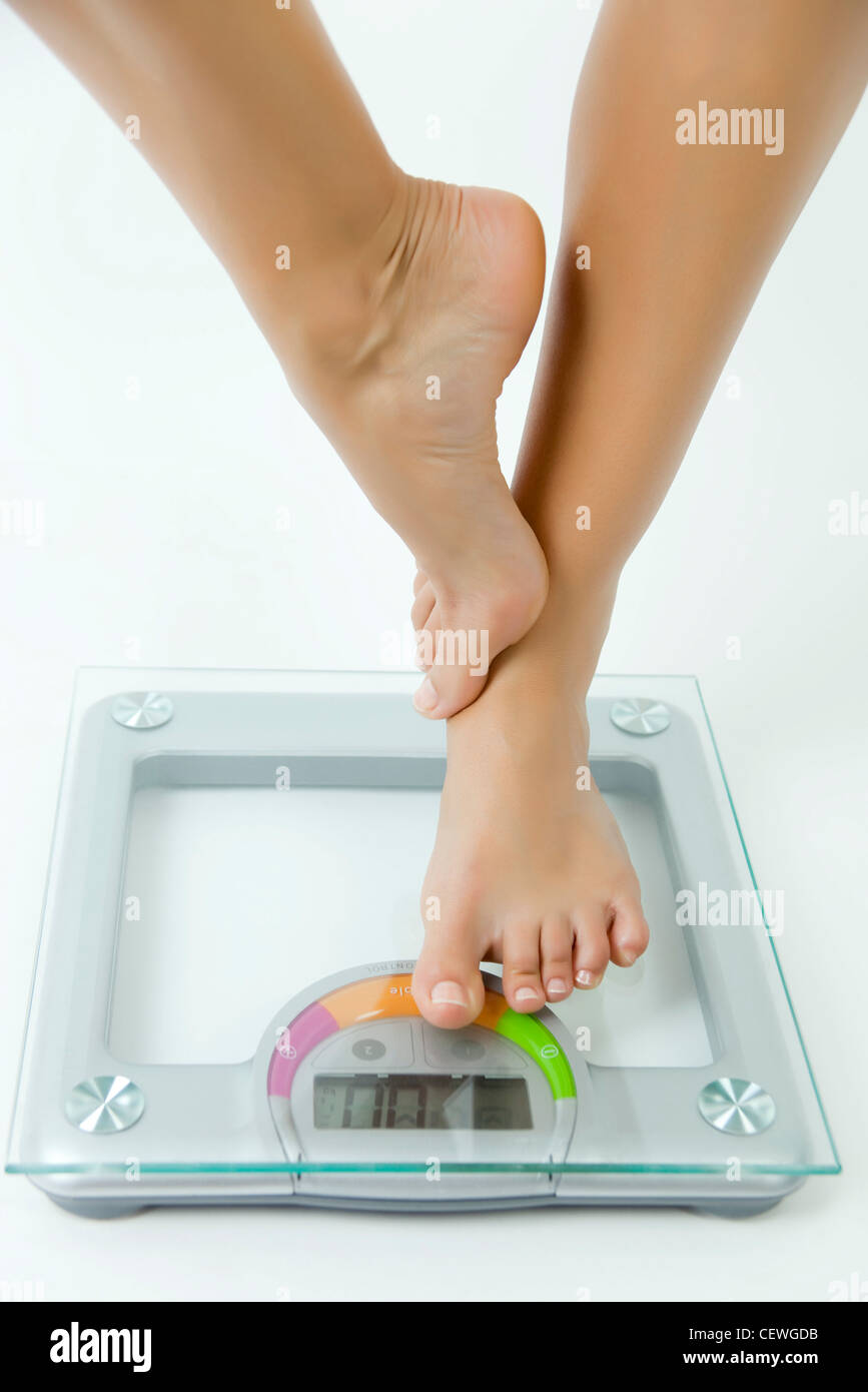 Femme debout sur une jambe sur l'échelle de bain, low section Banque D'Images