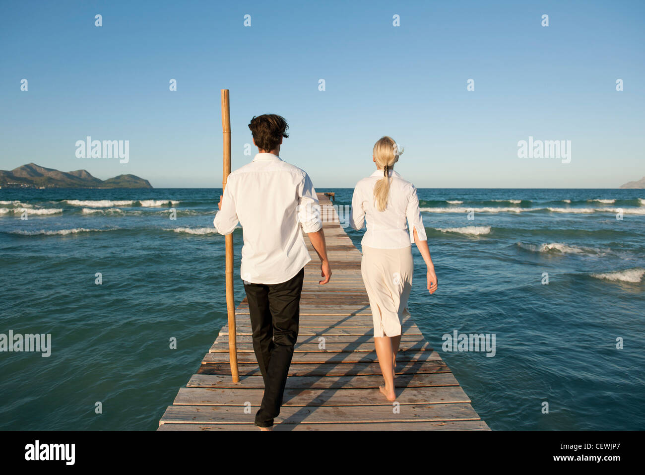 Couple en train de marcher sur la jetée au-dessus de l'eau, vue arrière Banque D'Images