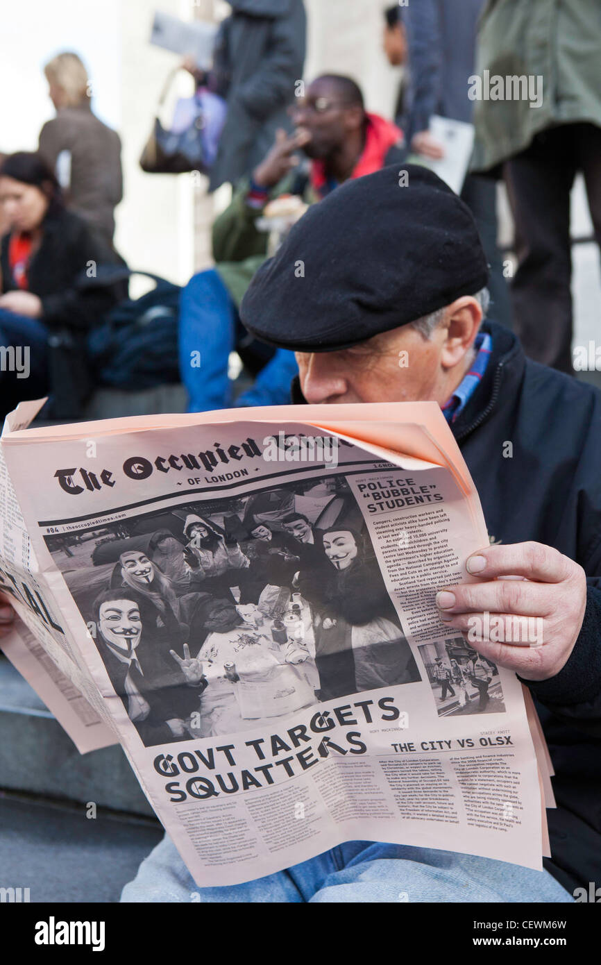 Un homme est assis en lisant un exemplaire du Times de Londres occupé à l'Occupy London OLSX de protestation. Banque D'Images