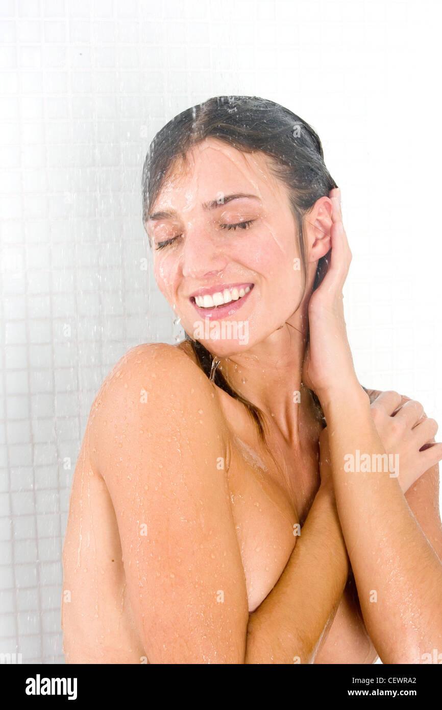 Long femme brunette cheveux douche à tête tourna les yeux fermés les bras sur le corps et les cheveux de la main en souriant montrant les dents Banque D'Images