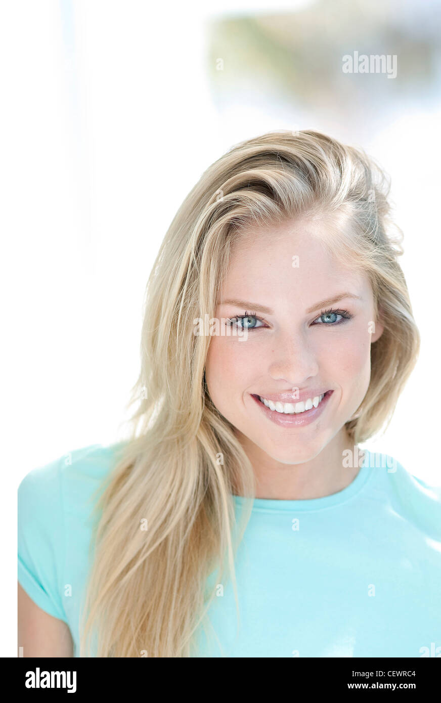Femme aux cheveux blonds, vêtu d'un haut turquoise pâle, smiling, looking at camera Banque D'Images