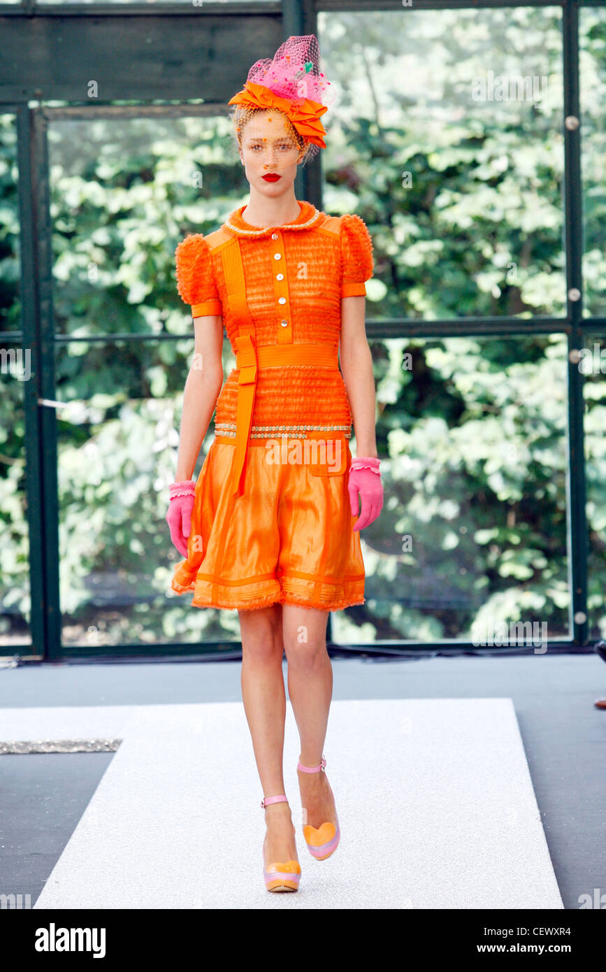 Orange et Rose : Raquel Zimmermann modèle allemand portant robe plissée ruban à plusieurs niveaux avec des gants, et déduits hat Banque D'Images