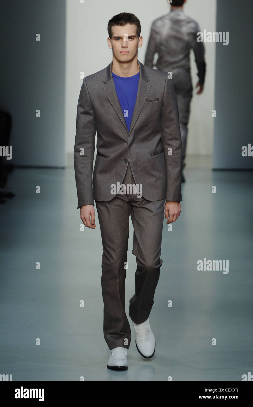 Calvin Klein Milan Prêt à Porter Automne Hiver Homme portant costume slim  gris foncé, avec t-shirt bleu et blanc chaussures Photo Stock - Alamy