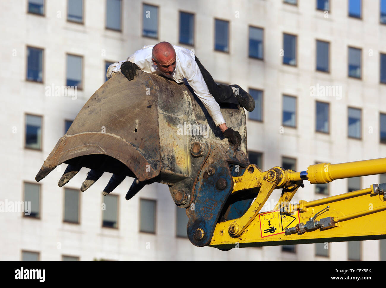 Un homme s'accroche à un mechanical digger dans le cadre de Transports Exceptionnels l'art de la performance sur le South Bank, Londres. Banque D'Images