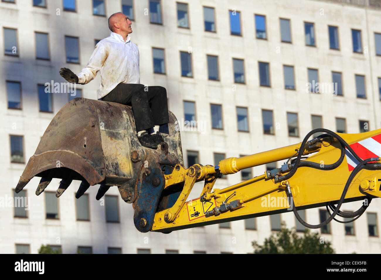 Un homme s'accroche à un mechanical digger dans le cadre de Transports Exceptionnels l'art de la performance sur le South Bank, Londres. Banque D'Images