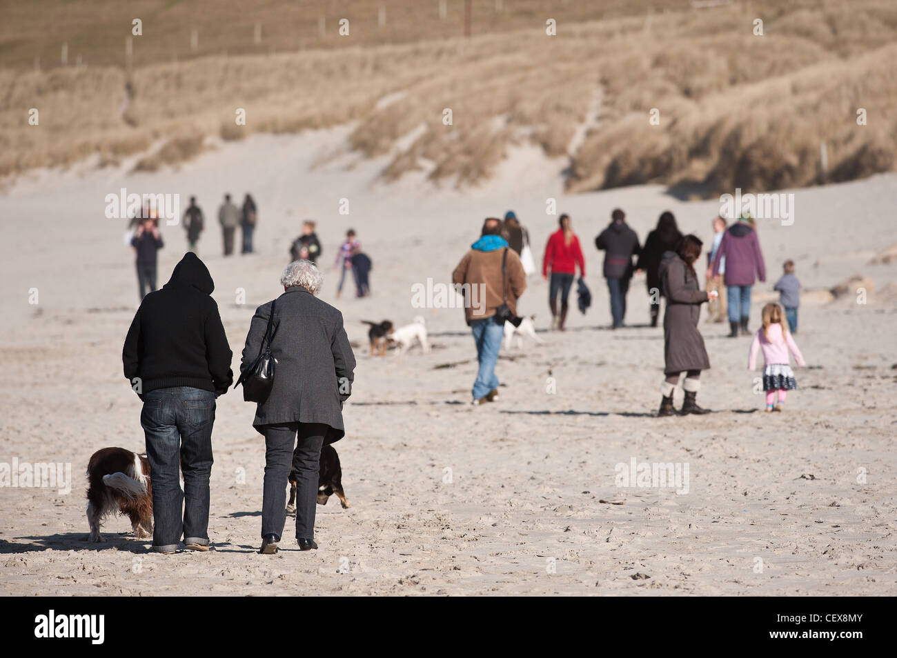 Les gens qui marchent sur la plage de Sennen par une froide journée ensoleillée Banque D'Images