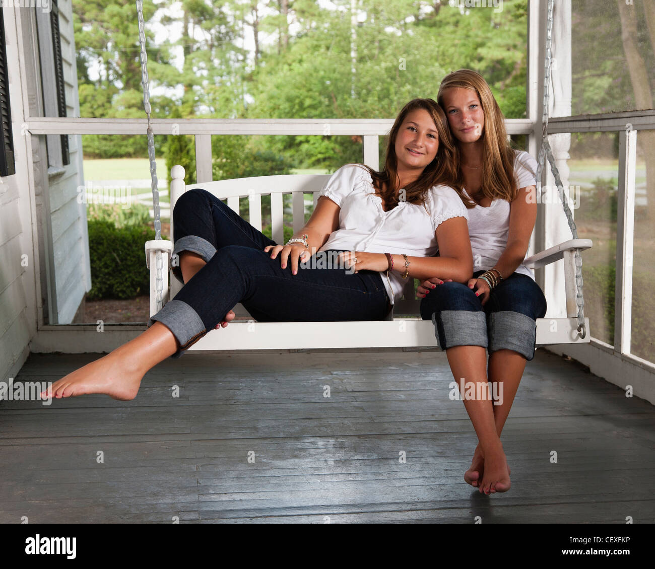 Young sisters sitting on porch swing ensemble Banque D'Images
