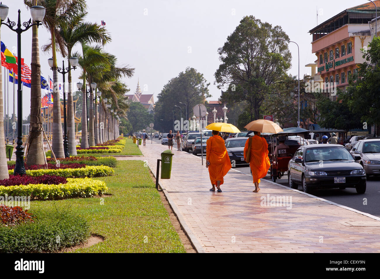 Deux moines en robe safran se protéger du soleil avec des parasols en marchant sur le chemin aux côtés de Sisowath Quay Banque D'Images