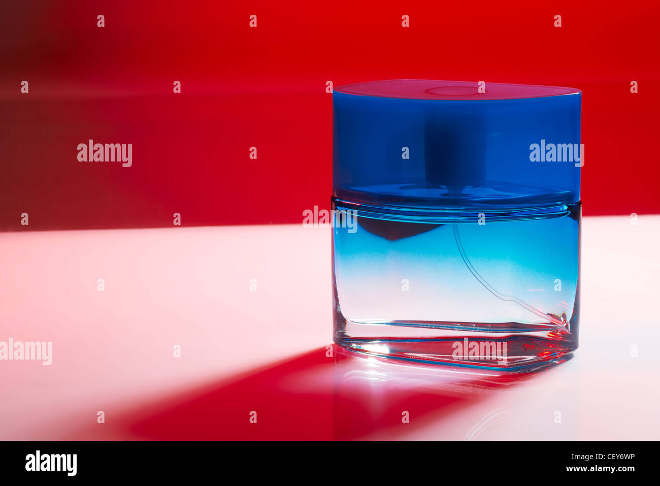 Flacon de parfum bleu sur fond violet avec ombre rouge Banque D'Images