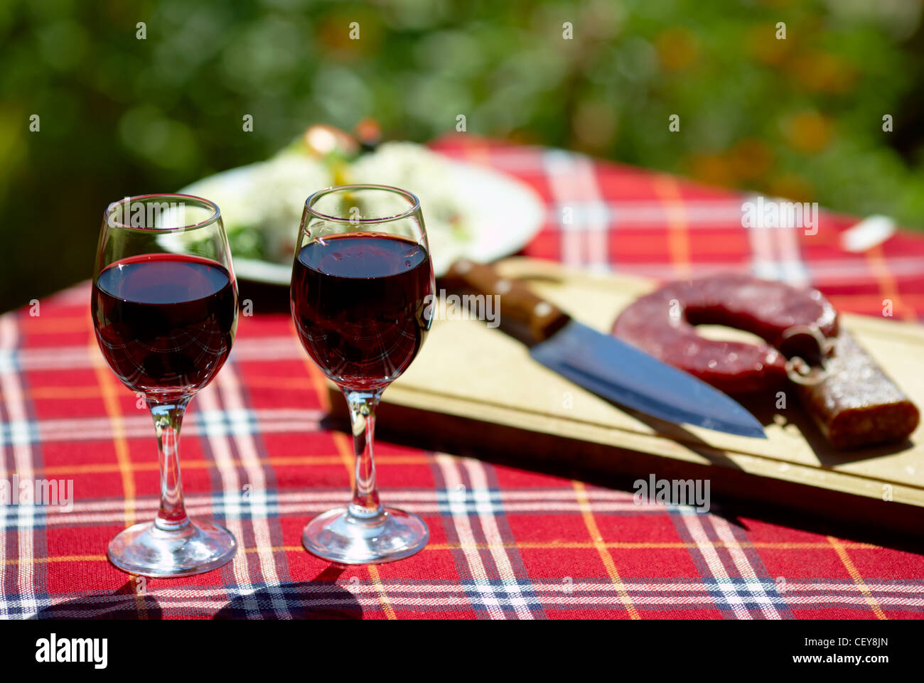 Verres de vin rouge sur une table, quelques fleurs en arrière-plan Banque D'Images