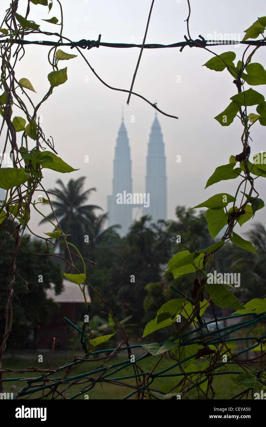Photo de l'éloigné Petronas Twin Towers, Kuala Lumpur, Malaisie, prises par le biais d'un fossé en une clôture. Banque D'Images