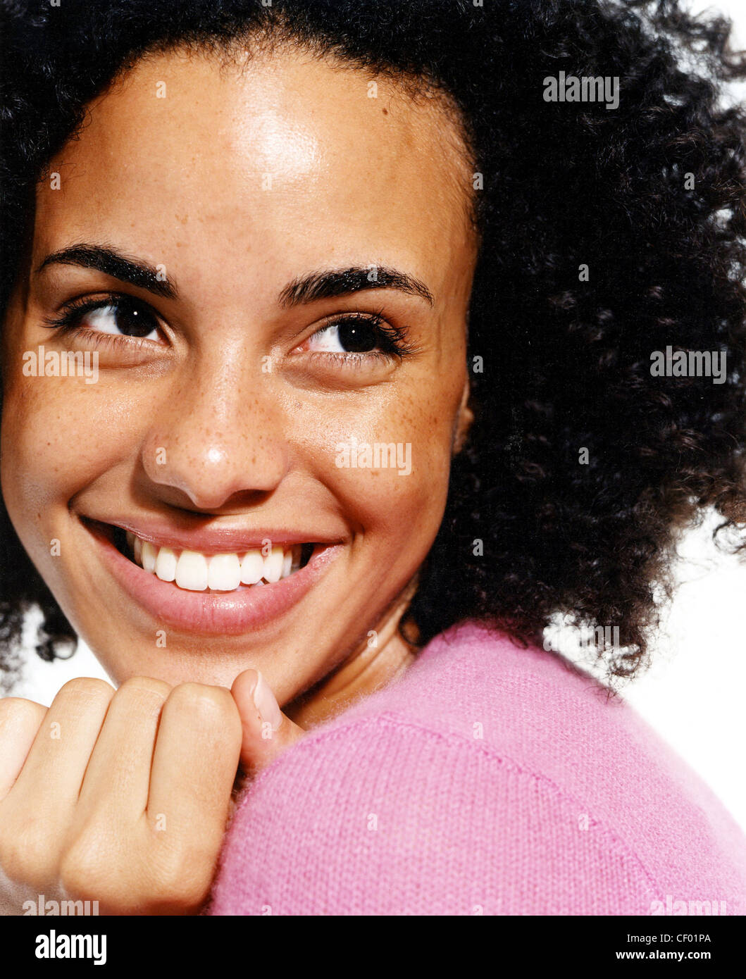 Femme brune avec des cheveux afro, vêtu d'un haut rose, souriant, à côté de la Banque D'Images