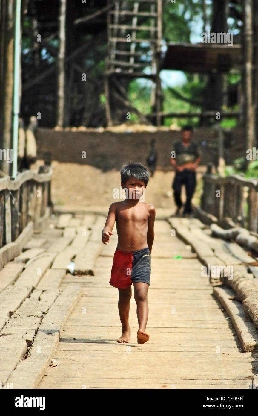 Un garçon marche sur un pont à Kompong Khleang, Cambodge Banque D'Images