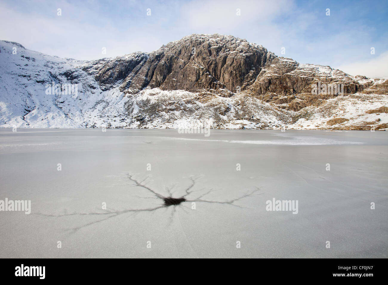 Un frozen Stickle Tarn avec les patrons des fissures dans la glace, au-dessus de la vallée de Langdale dans le Lake District, UK, avec Pavey Ark Banque D'Images