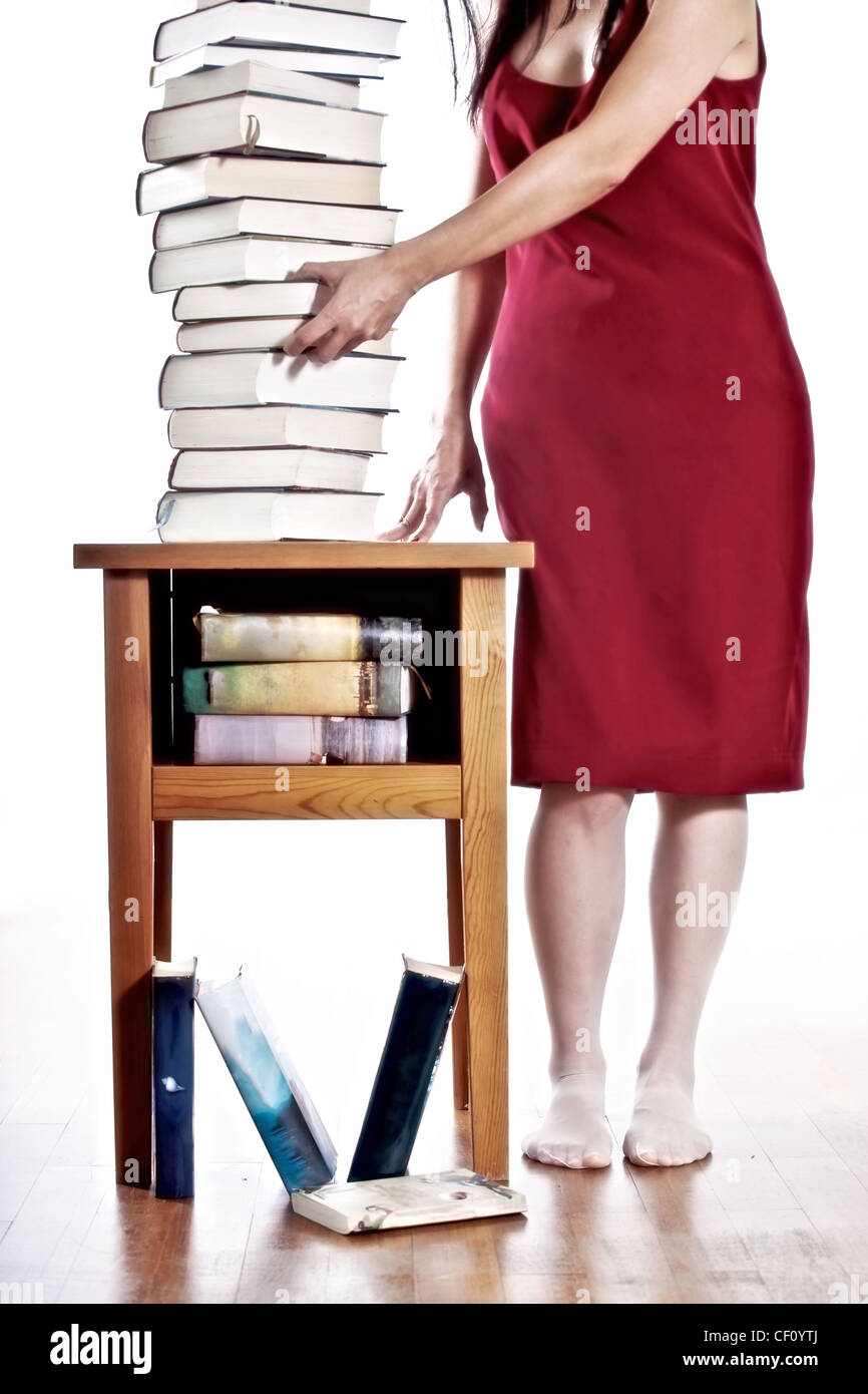 Une femme dans une robe rouge debout à côté d'une pile de livres Banque D'Images