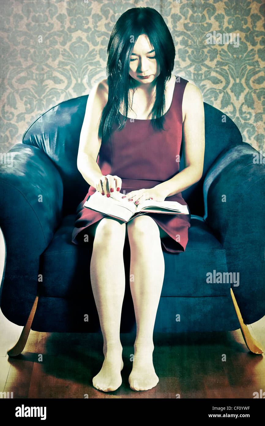 Femme assise sur une chaise et la lecture d'un livre Banque D'Images