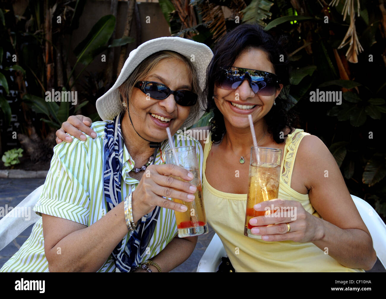 Mother and Daughter hugging avec bonheur et profiter des vacances avec des boissons fraîches dans le jardin à beach resort en Afrique du Sud. Banque D'Images