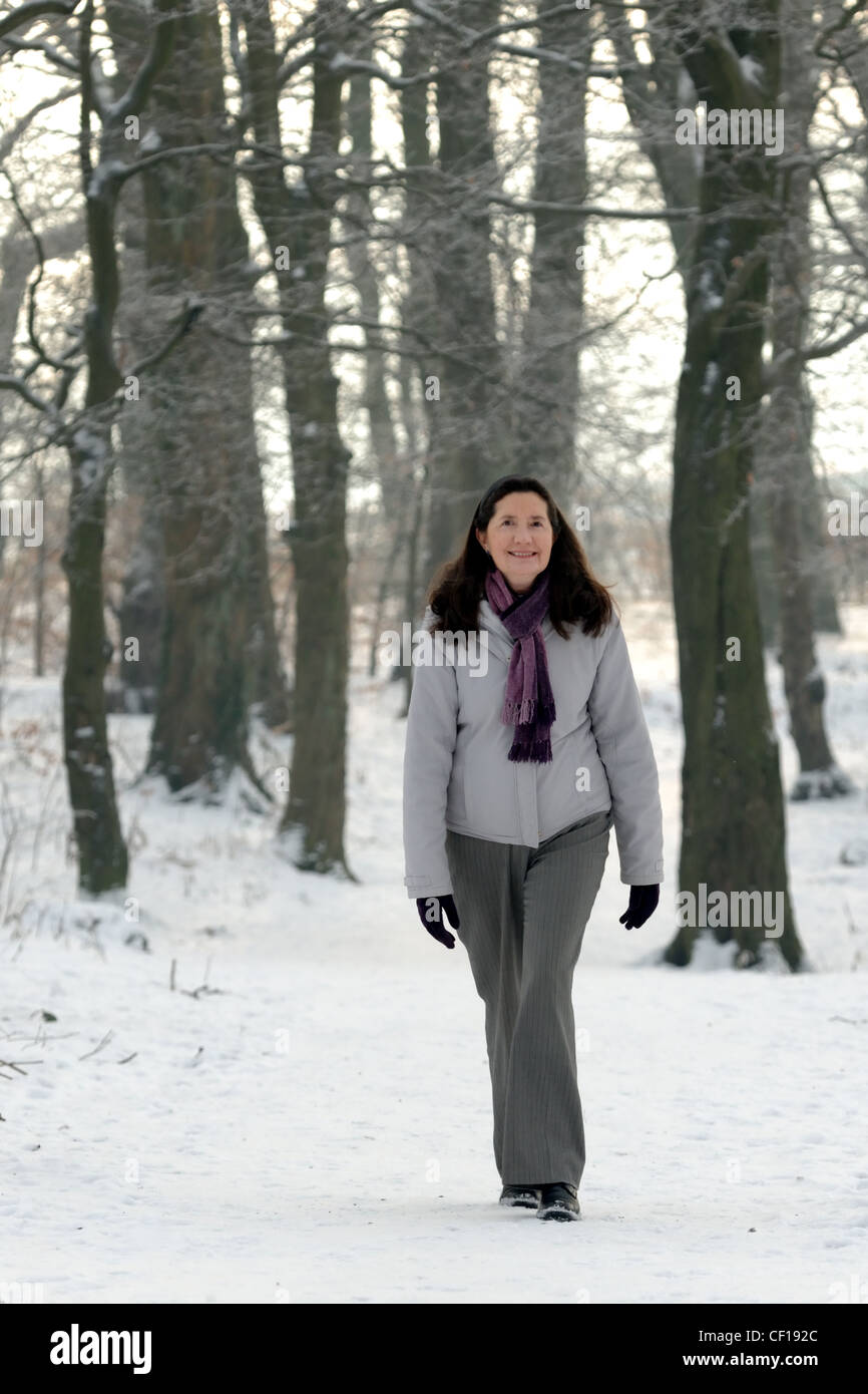 Femme d'âge moyen de marcher dans la neige Banque D'Images